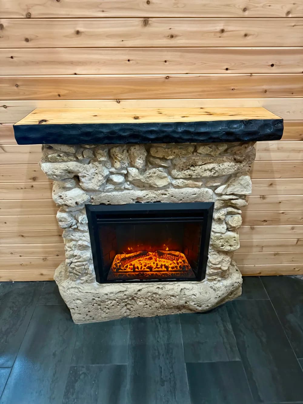 The finished mantel installed above a fieldstone fireplace against a cedar wall