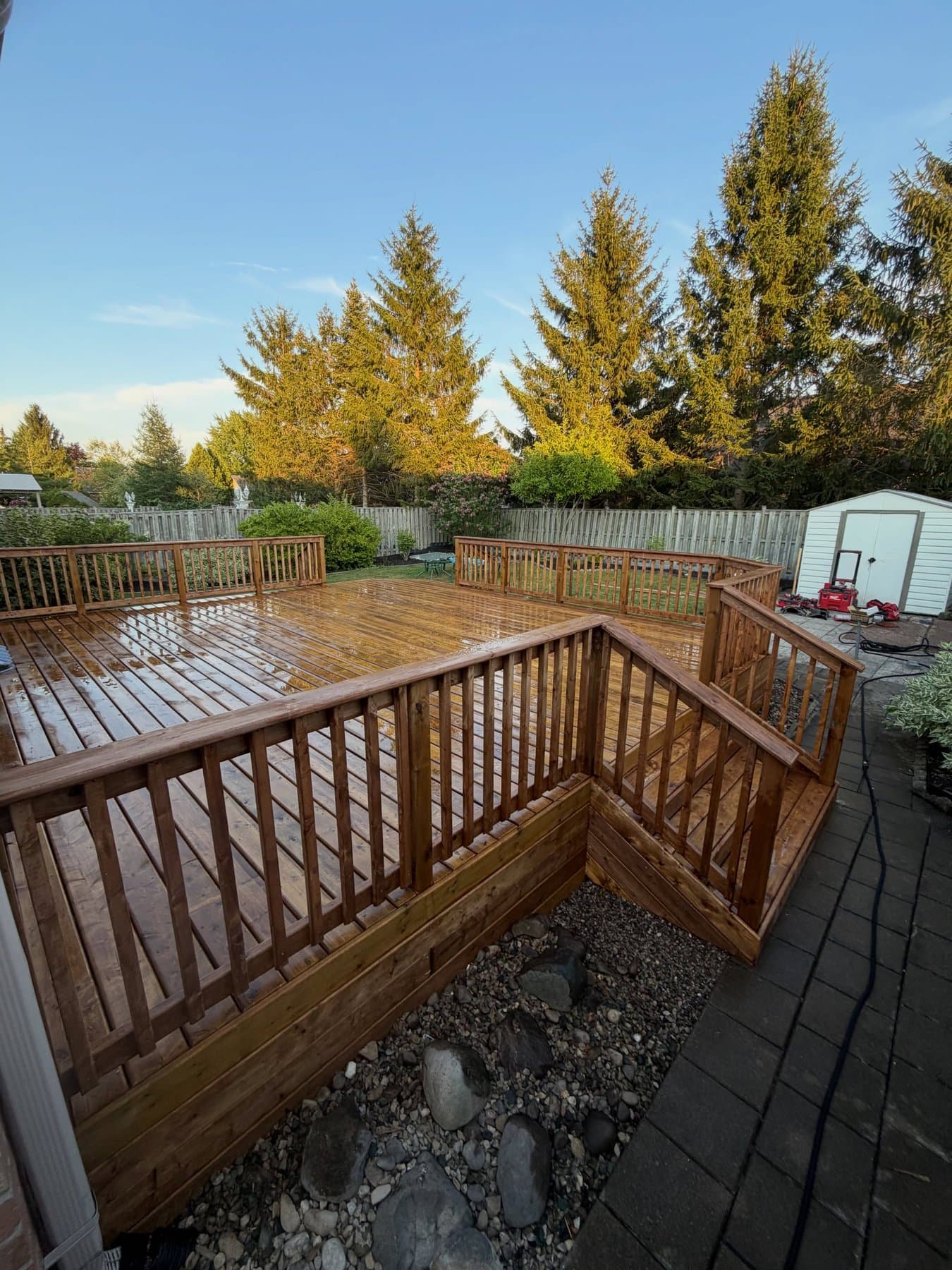Corner of the finished deck at golden hour with tools and a storage shed in the background