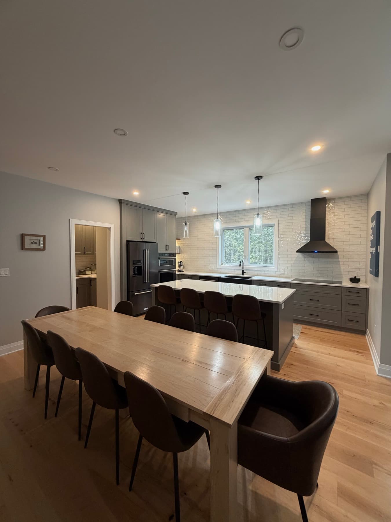 Open kitchen and dining room with a live-edge table, leather chairs and pendant lighting over the island