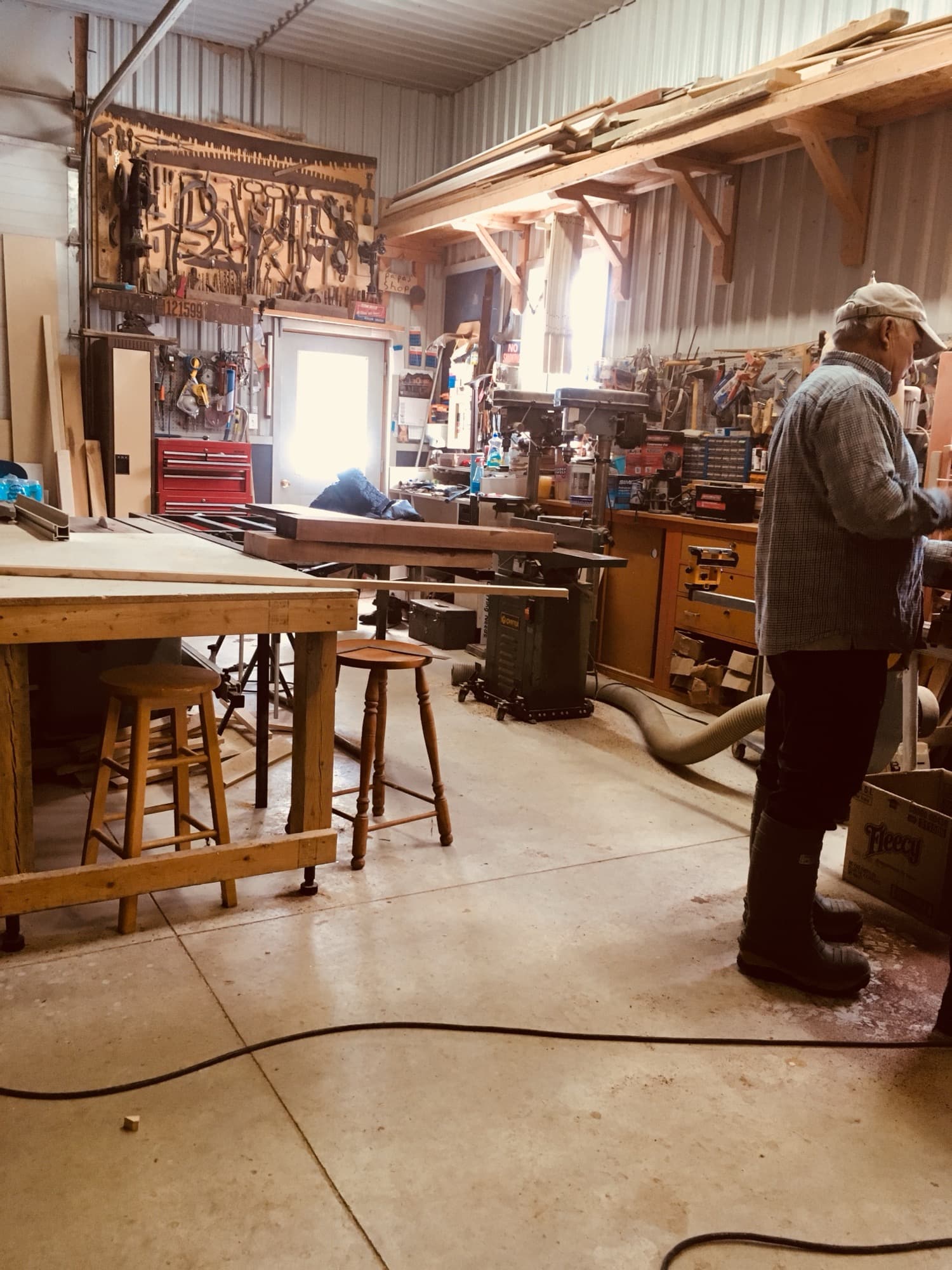 Papa in his workshop, surrounded by hand tools, lumber and a drill press